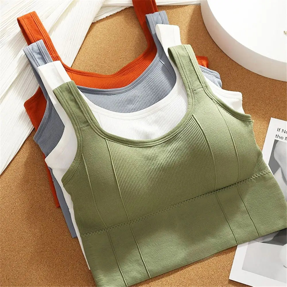 Stack of green, orange, gray, and white tank tops on a cork board background
