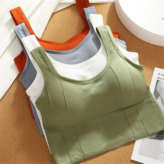 Stack of green, orange, gray, and white tank tops on a cork board background